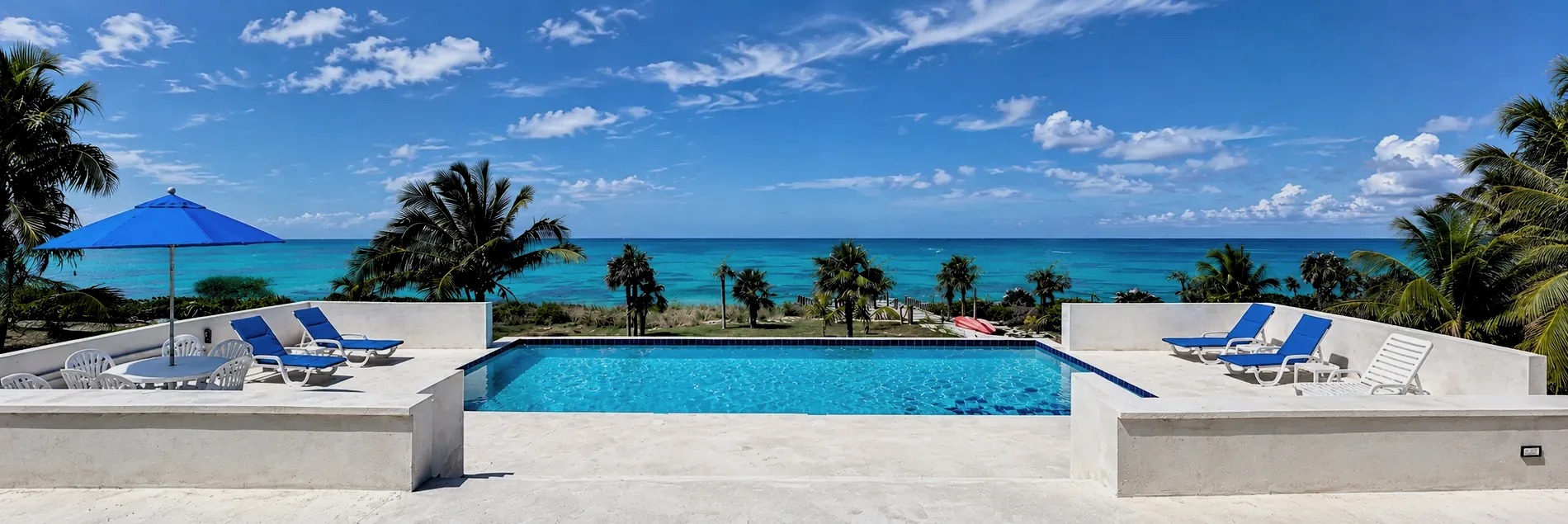 The pool at Seaview Villa looking out over the lawn and palms to the turquoise Atlantic under a blue sky